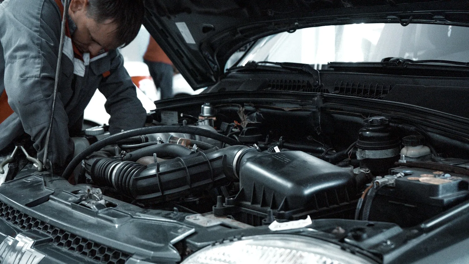 Mechaniker bei der Arbeit im Motorraum eines Fahrzeugs
